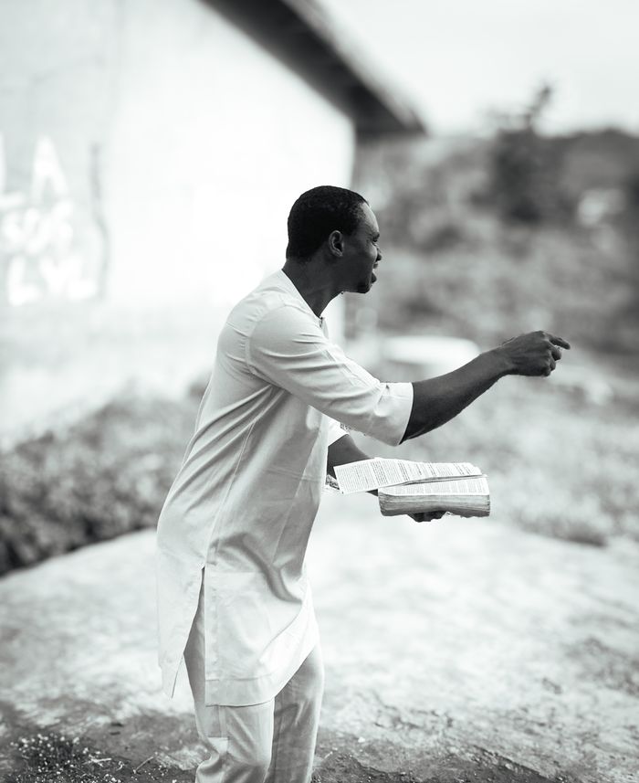 About Black and white photo of an African preacher energetically giving a sermon outdoors.