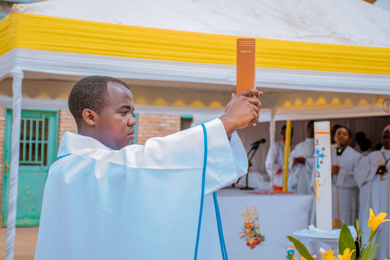 Mastering the First Impression: Your intriguing post title goes here Priest in white robe elevates a Bible during an outdoor religious ceremony.