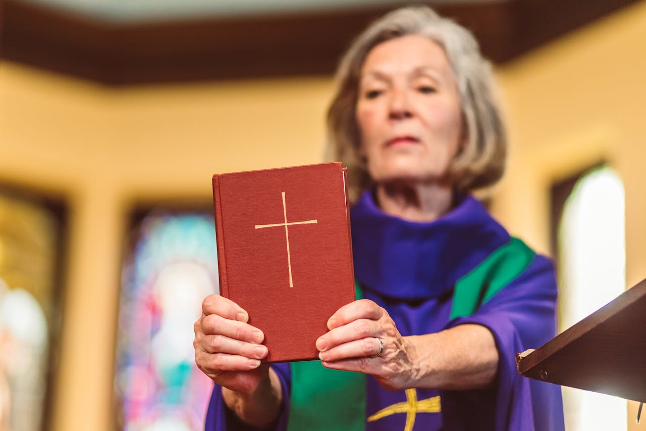 The Art of Drawing Readers In: Your attractive post title goes here An elderly female priest holding a Bible inside a church setting.